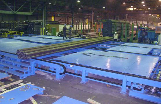Finishing line with blue conveyor system and bundled bar steel in a factory hall