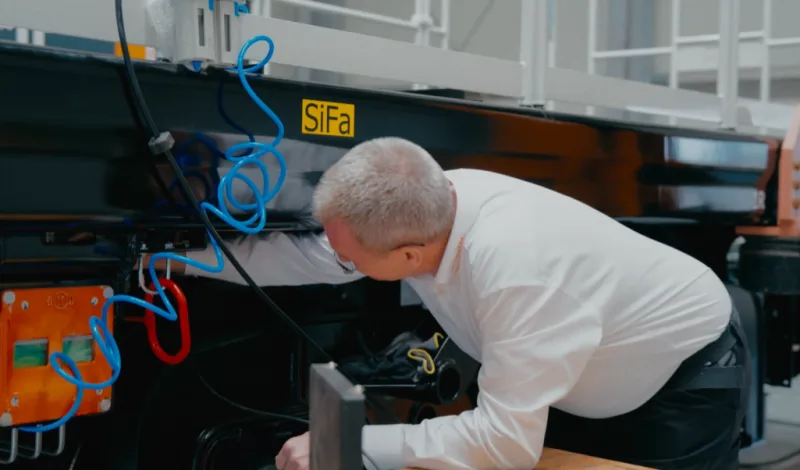 Employee checking the wiring underneath the body of a platform car