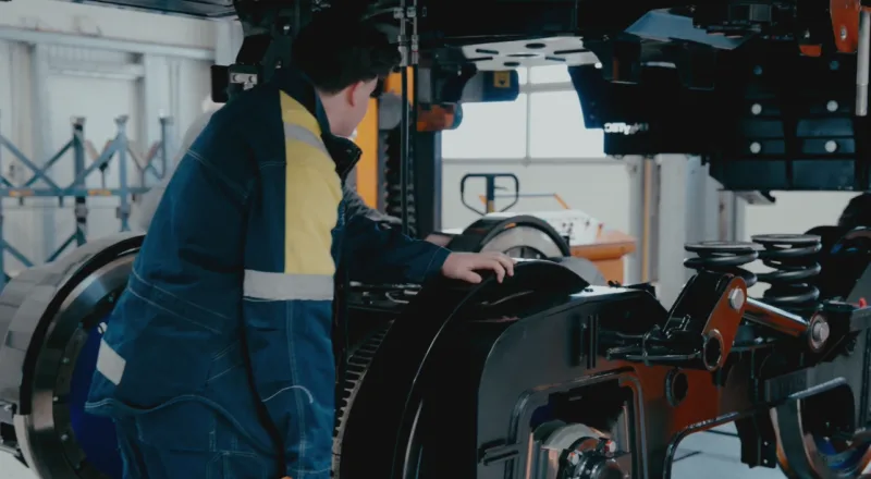 Worker in protective clothing assembling a bogie with coil springs